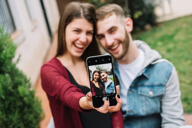 Pareja joven enamorada haciendo selfie en jardín