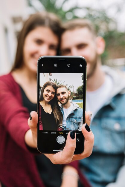 Pareja joven enamorada haciendo selfie en jardín