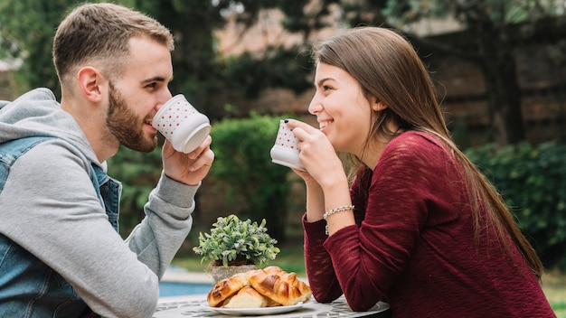 Pareja joven enamorada tomando café en jardín