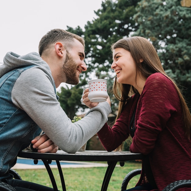 Pareja joven enamorada tomando café en jardín