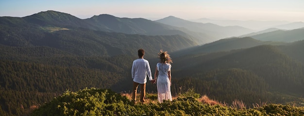 Foto gratuita pareja joven, enamorado, posición, en, herboso, colina, en, montañas