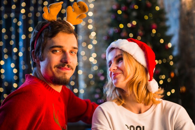 Pareja joven enfrente de árbol de navidad