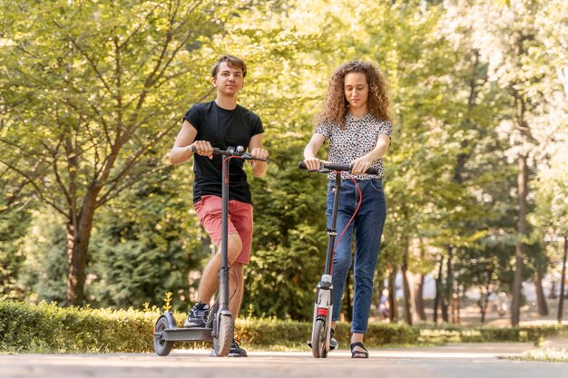 Pareja joven, equitación, scooters, aire libre