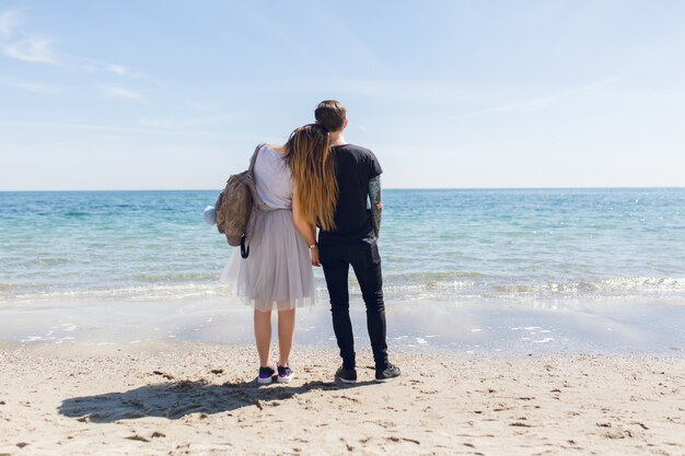 Pareja joven está de pie cerca del mar