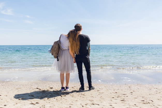 Pareja joven está de pie cerca del mar