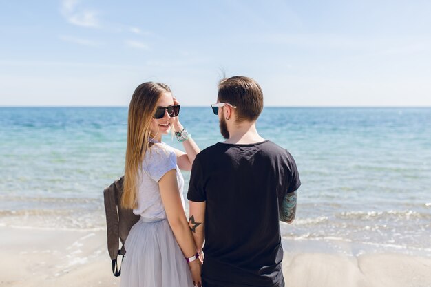 Pareja joven está de pie cerca del mar