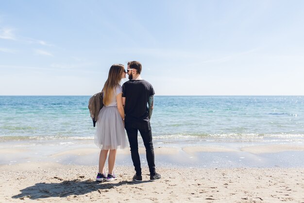 Pareja joven está de pie en la playa cerca del mar