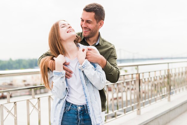 Pareja joven feliz en el amor de pie cerca de barandilla metálica