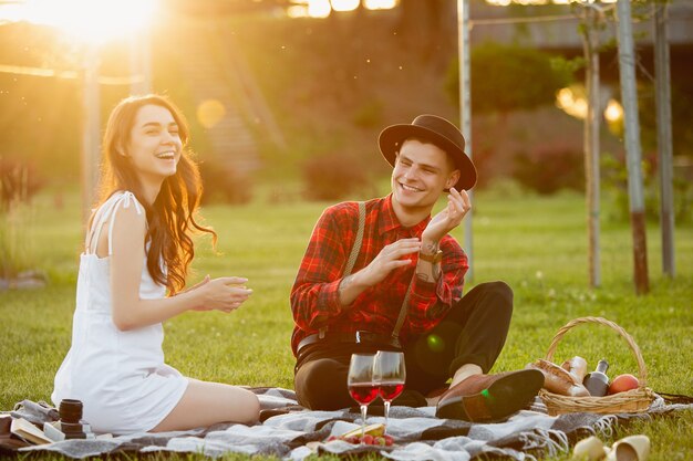 Pareja joven y feliz caucásica disfrutando de un picnic en el parque el día de verano