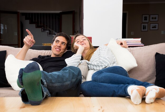 Pareja joven feliz descansando en el sofá en casa