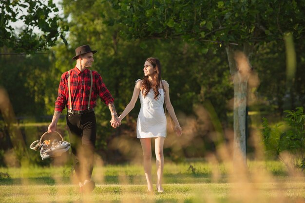 Pareja joven y feliz disfrutando de un picnic en el parque en día de verano