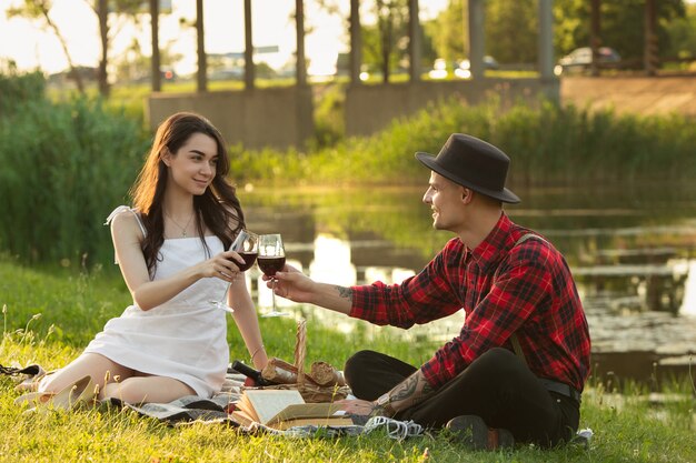 Pareja joven y feliz disfrutando de un picnic en el parque en día de verano