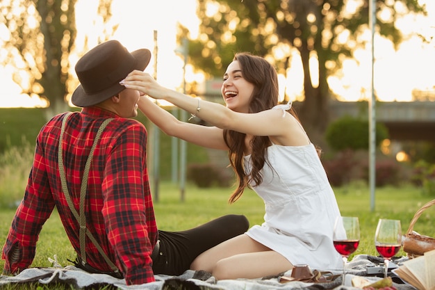 Pareja joven y feliz disfrutando de un picnic en el parque en día de verano