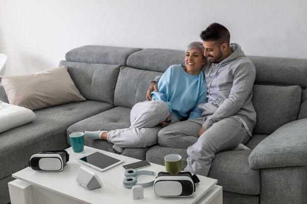 Una pareja joven feliz está acostada en un sofá nuevo en la sala de estar y descansando. Apartamento moderno y luminoso con muebles elegantes