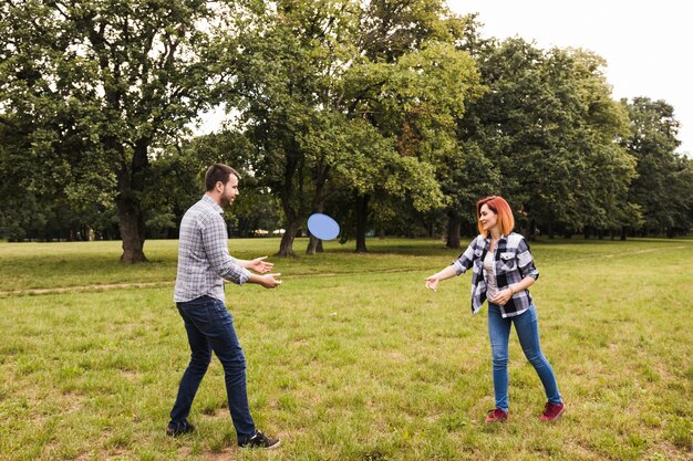 Pareja joven feliz jugando con disco volador en el jardín