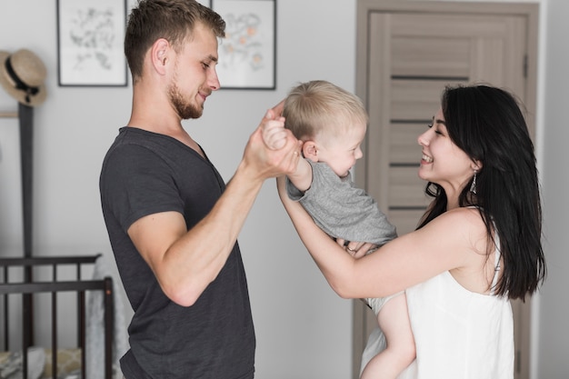 Foto gratuita pareja joven feliz jugando con su pequeño hijo en casa