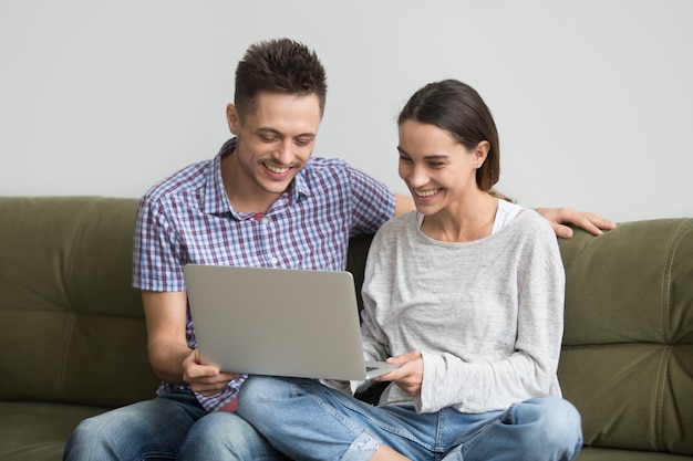 Foto gratuita pareja joven feliz riendo mientras hace video llamada en la computadora portátil