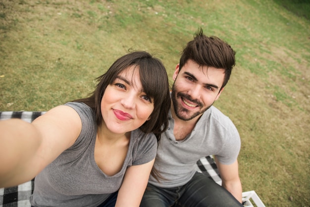 Foto gratuita pareja joven feliz tomando selfie en el parque