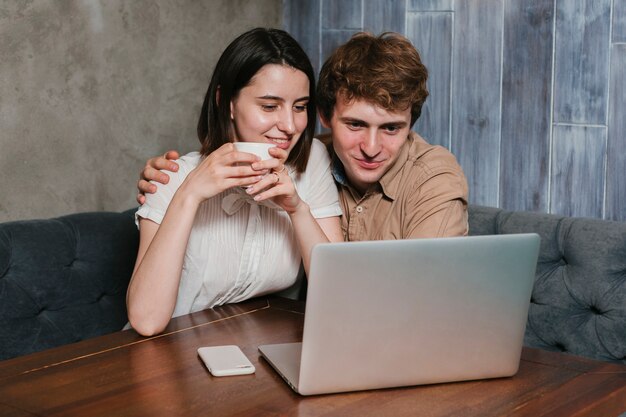 Pareja joven frente a la computadora portátil sonriendo