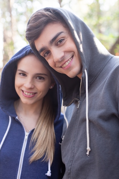 Pareja joven con una gran sonrisa llevando sudaderas con capucha