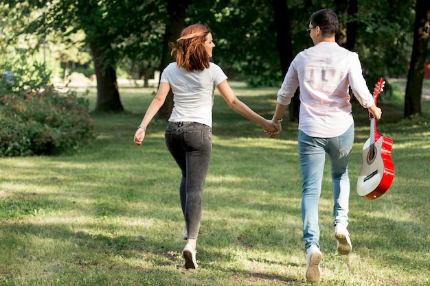 Pareja joven con una guitarra alejándose