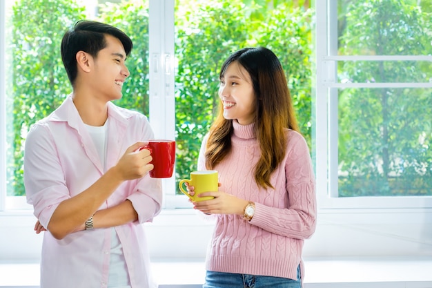 Pareja joven hablando y beber bebidas en casa