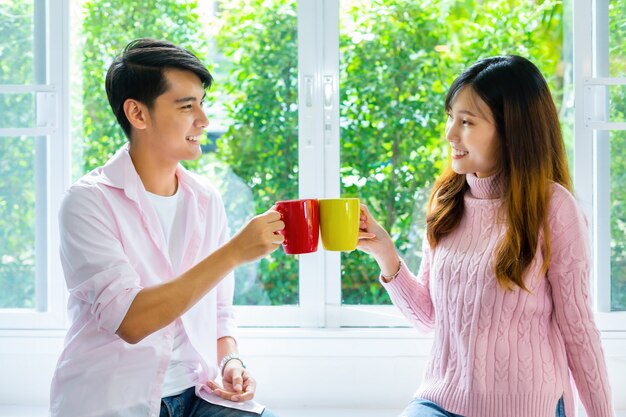 Pareja joven hablando y beber bebidas en casa