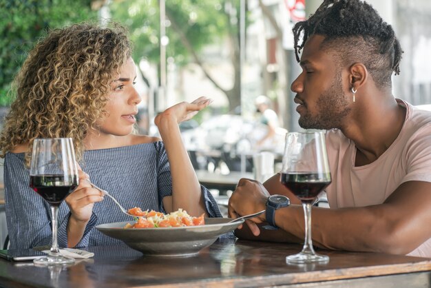 Pareja joven hablando y disfrutando mientras almuerzan juntos en un restaurante.