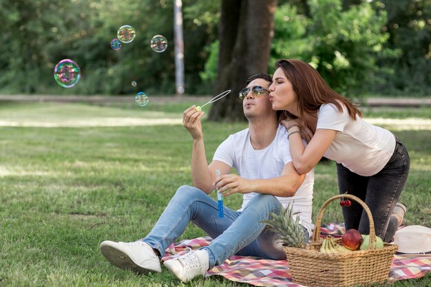 Pareja joven haciendo burbujas en picnic