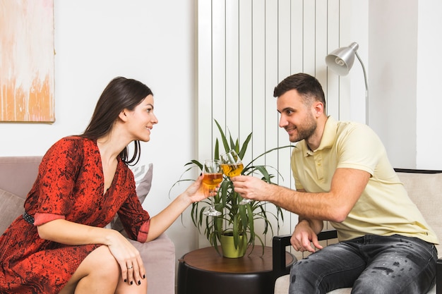 Foto gratuita pareja joven haciendo clic en las copas sentado cara a cara