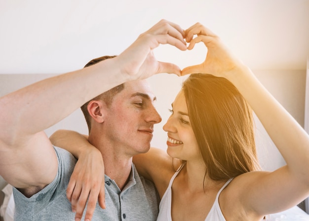 Pareja joven haciendo forma de corazón de manos