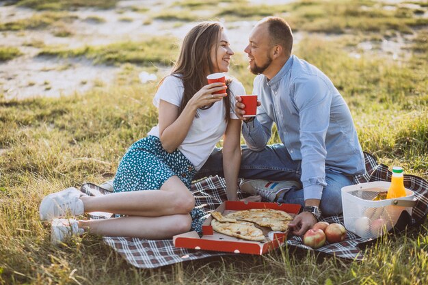 Pareja joven haciendo un picnic con pizza en el parque