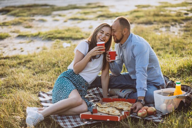 Pareja joven haciendo un picnic con pizza en el parque