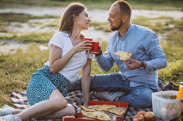 Pareja joven haciendo un picnic con pizza en el parque