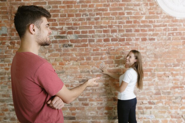 Pareja joven haciendo reparación de apartamentos juntos ellos mismos. Hombre y mujer casados haciendo remodelación o renovación de la casa