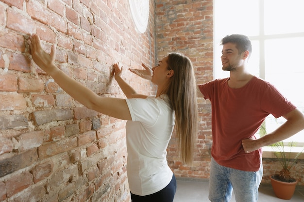 Pareja joven haciendo reparación de apartamentos juntos ellos mismos. Hombre y mujer casados haciendo remodelación o renovación de la casa