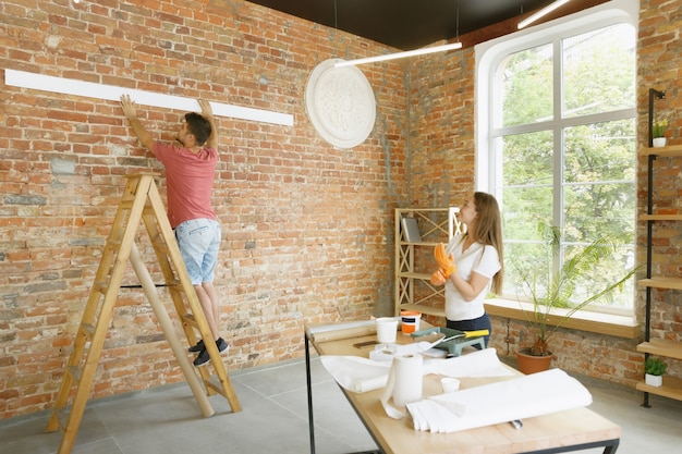 Foto gratuita pareja joven haciendo reparación de apartamentos juntos ellos mismos. hombre y mujer casados haciendo remodelación o renovación de la casa