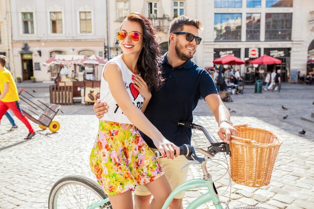 Pareja joven hermosa hipster enamorada caminando con bicicleta en la calle de la ciudad vieja