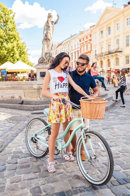 Pareja joven hermosa hipster enamorada caminando con bicicleta en la calle de la ciudad vieja