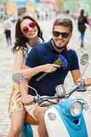 Foto gratuita pareja joven hermosa hipster montando en moto calle de la ciudad