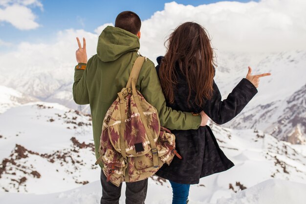 Pareja joven hermosa hipster senderismo en las montañas, viajes de vacaciones de invierno, hombre mujer enamorada vista desde atrás