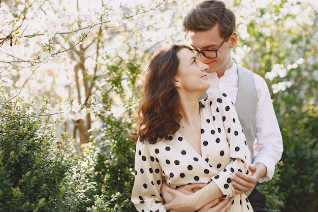 Foto gratuita pareja joven hombre y mujer en un jardín floreciente