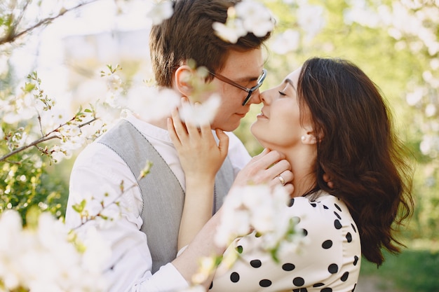 Foto gratuita pareja joven hombre y mujer en un jardín floreciente