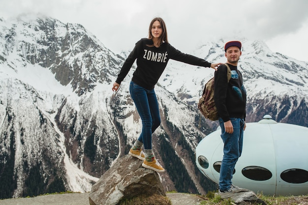 Pareja joven inconformista enamorada caminando en las montañas