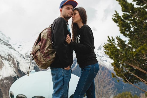 Pareja joven inconformista enamorada caminando en las montañas