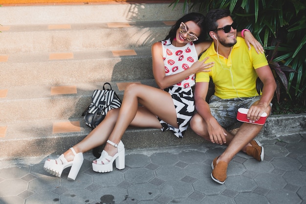 Pareja joven inconformista enamorada, escuchando música en el altavoz, sonriendo feliz, divirtiéndose, traje de verano, vacaciones tropicales, gafas de sol