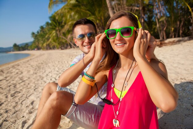 Pareja joven inconformista enamorada, playa tropical, vacaciones, estilo de moda de verano, gafas de sol, auriculares