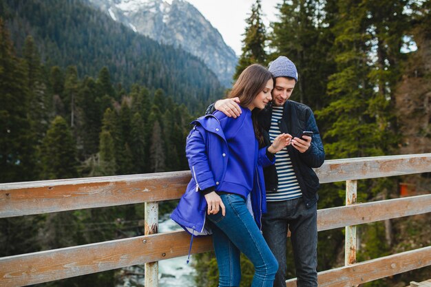 Pareja joven inconformista enamorada en vacaciones de invierno en las montañas