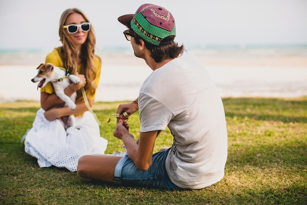 Pareja joven inconformista con estilo en el amor caminando y jugando con perro