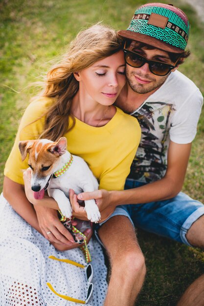 Foto gratuita pareja joven inconformista con estilo en el amor sentado en la hierba jugando al perro en la playa tropical